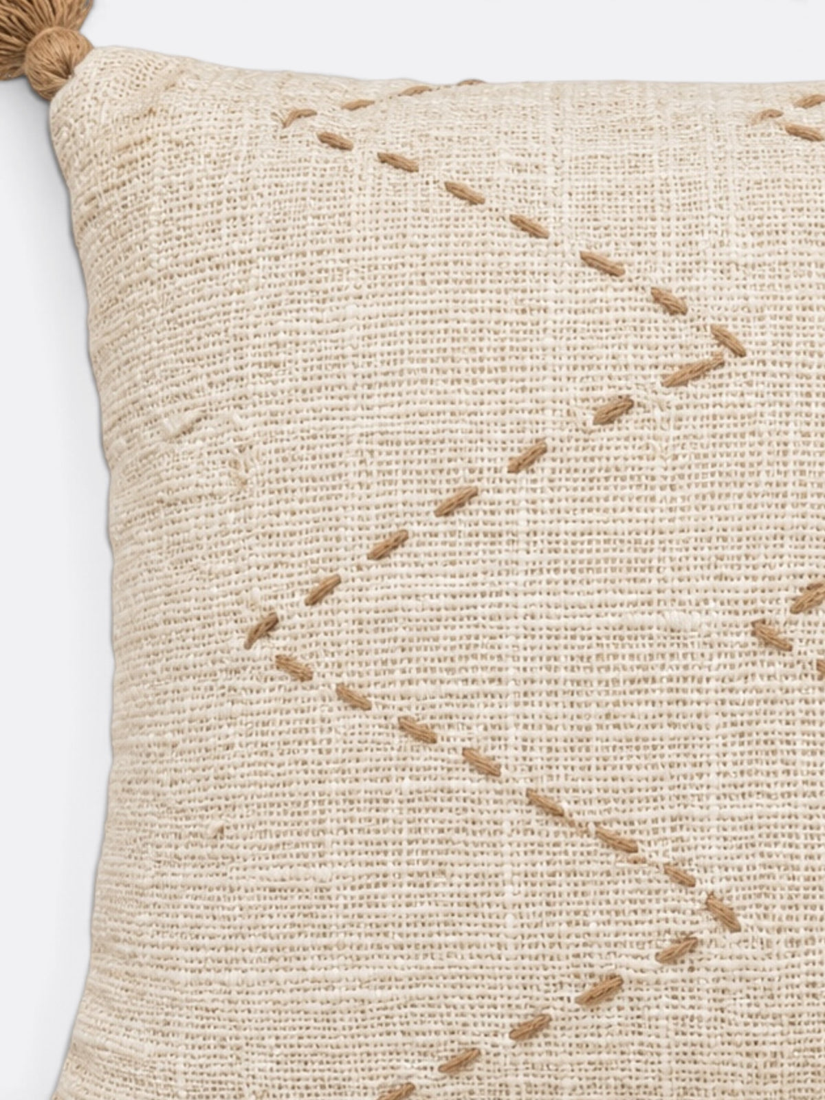 Détail des franges de raphia et du tissage beige écru du coussin balinais en coton
