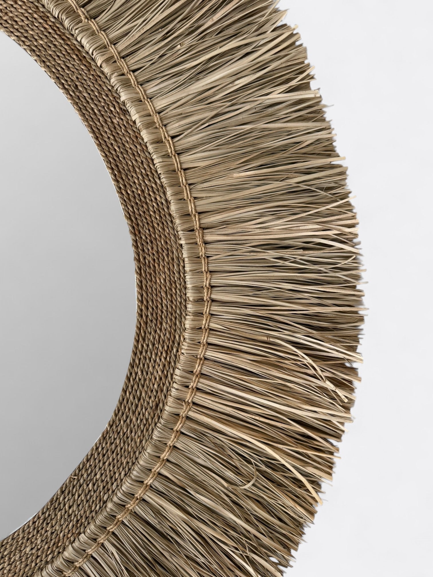 Gros plan sur le tressage artisanal du miroir ovale Naya : raphia et rotin naturel