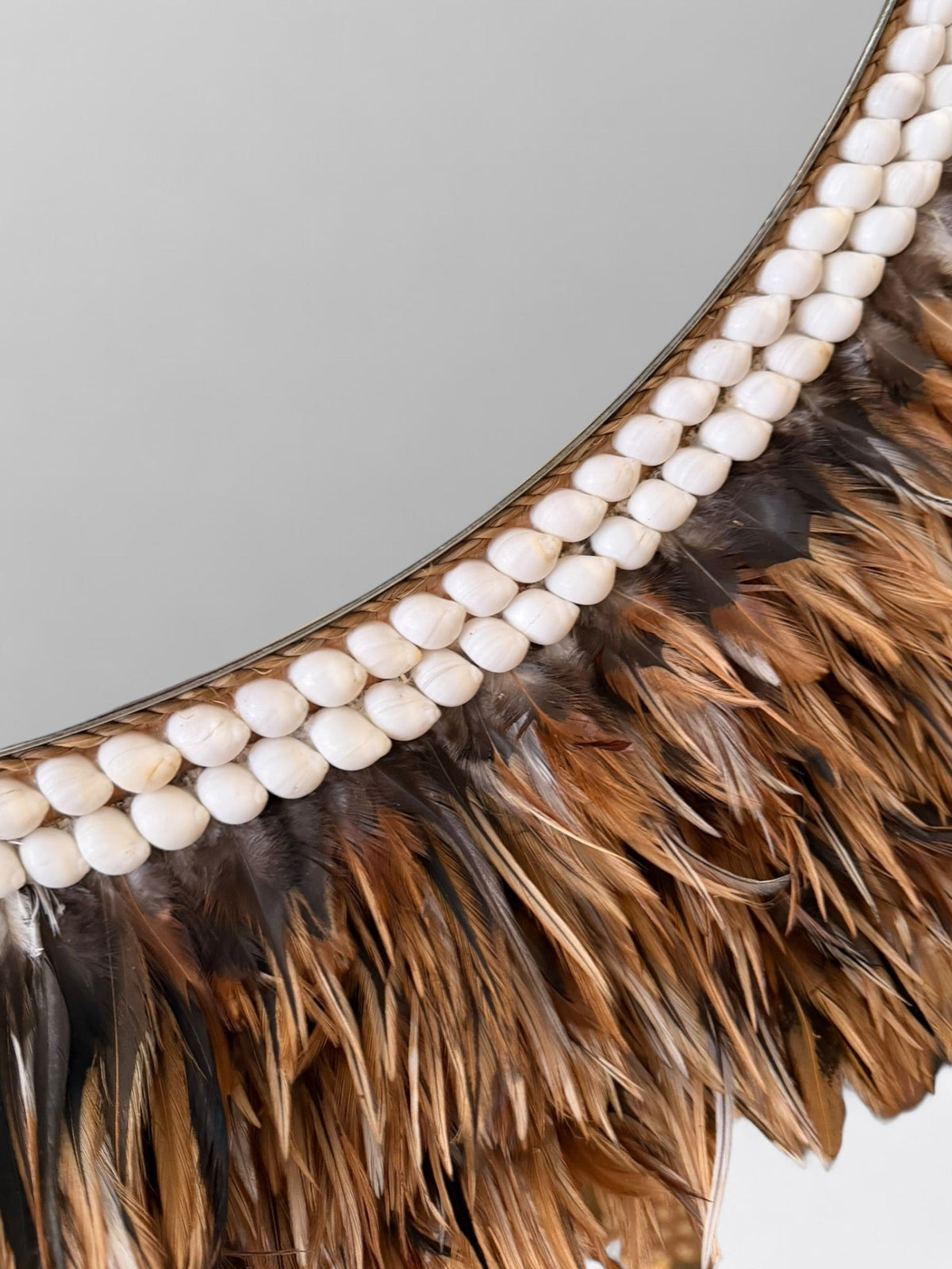 Gros plan sur les plumes douces et les coquillages naturels du grand miroir artisanal Peniah