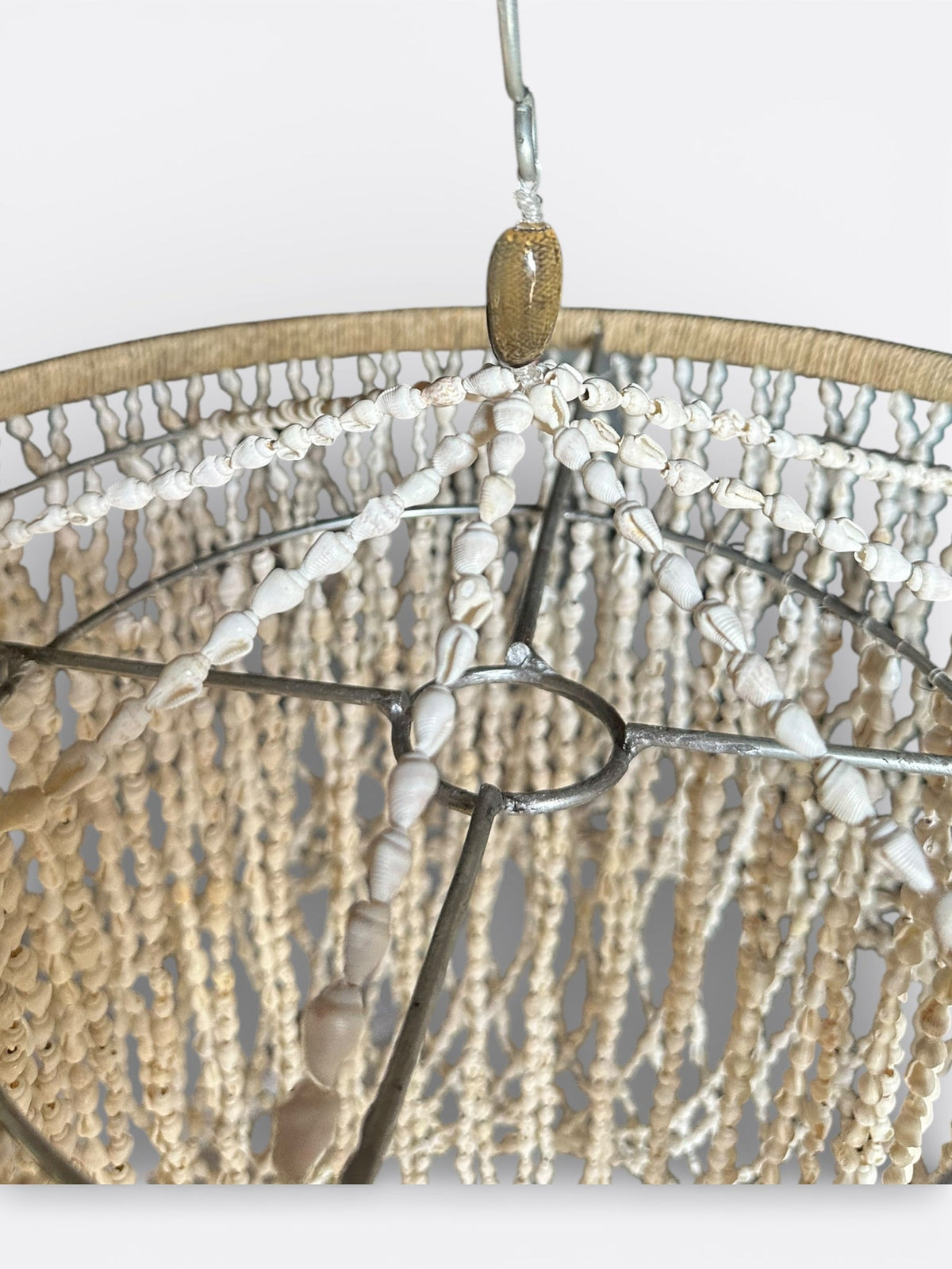 Détail du macramé et des coquillages blancs du lustre Megeng