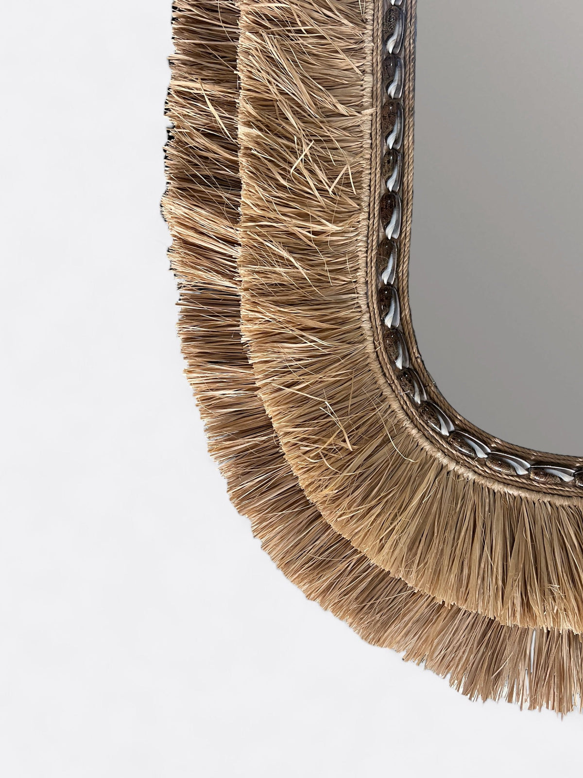 Gros plan sur les coquillages naturels et le tressage en raphia du miroir ovale Dayut