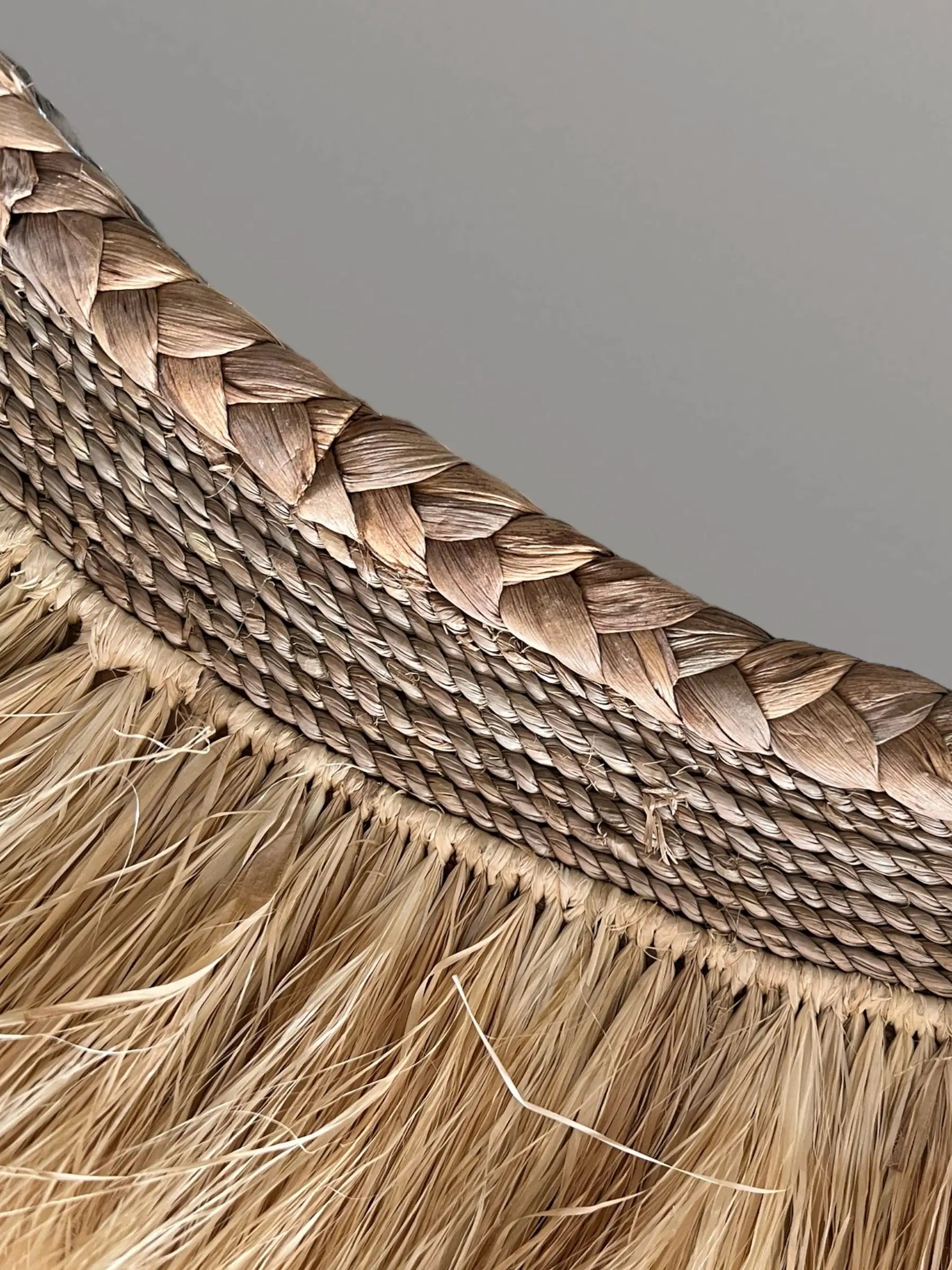 Détail de la texture organique et des fibres de raphia naturel du miroir Ida