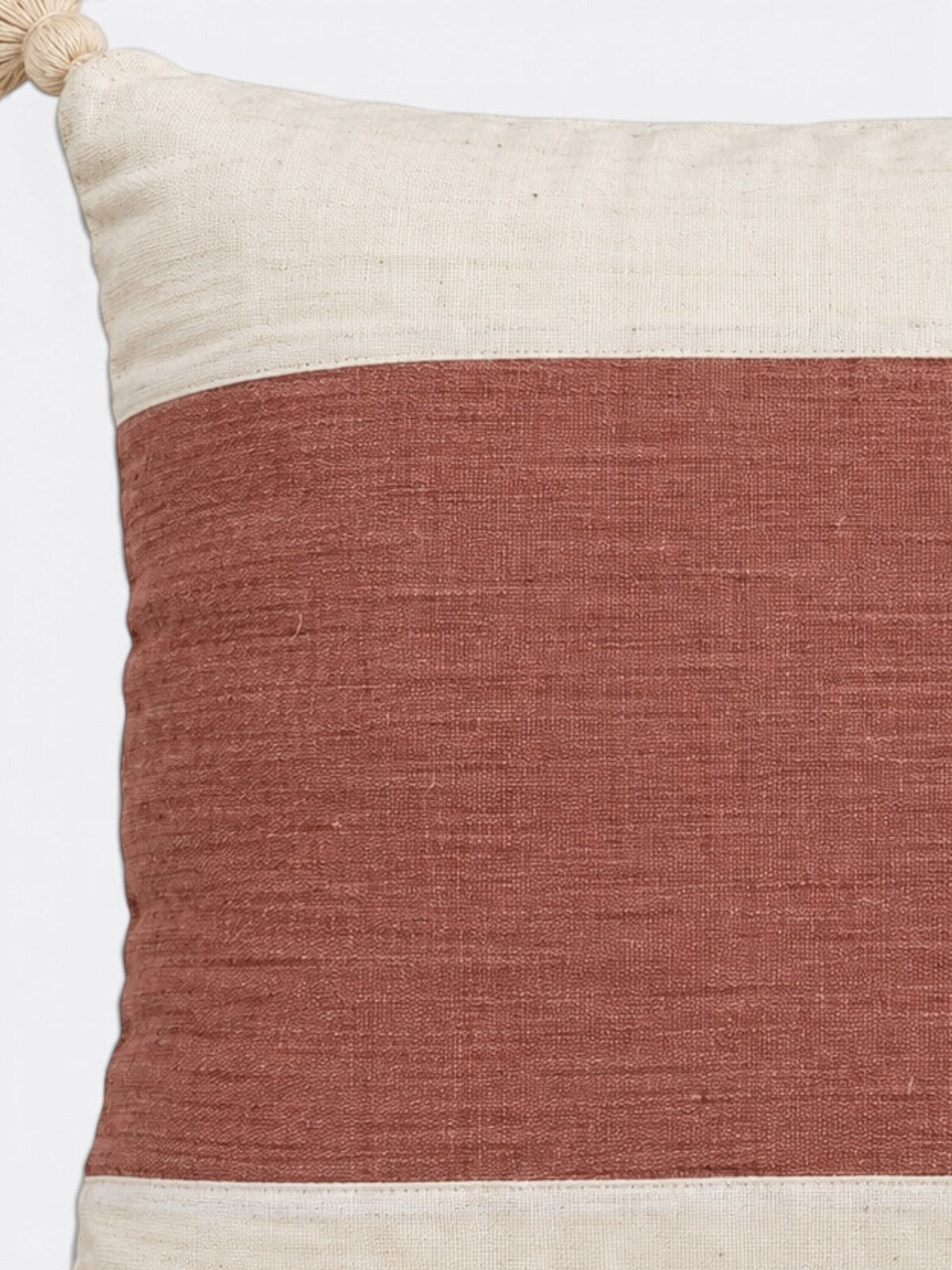 Détail d'un pompon et du tissage blanc et rouge du coussin balinais en coton