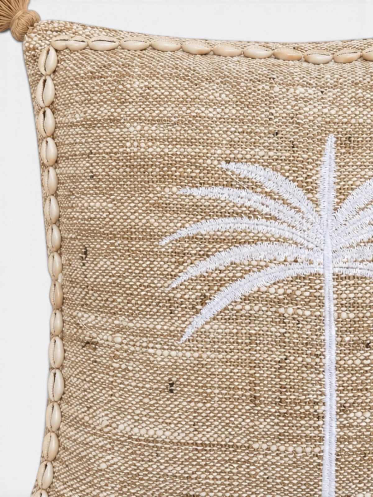 Détail de la broderie palmier blanche et des coquillages cauris sur le coussin en jute