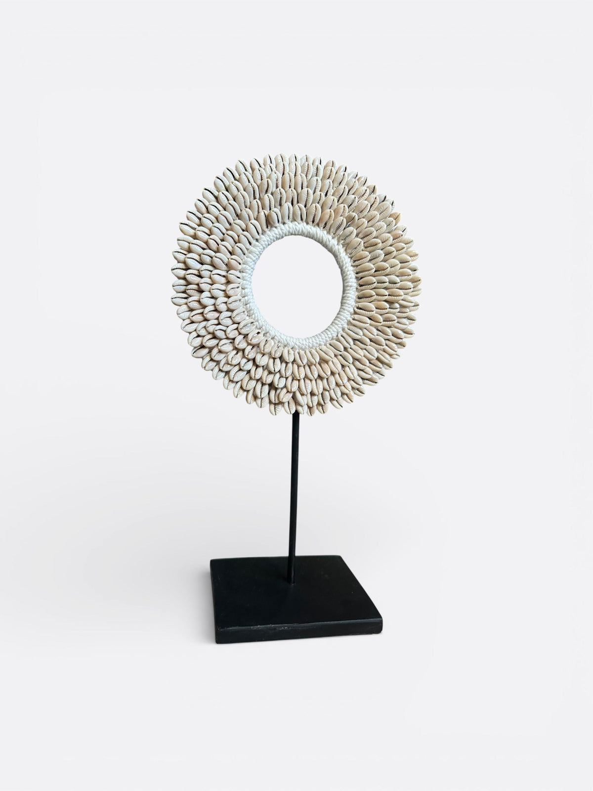 Collier Nari en coquillages cauri accroché au mur